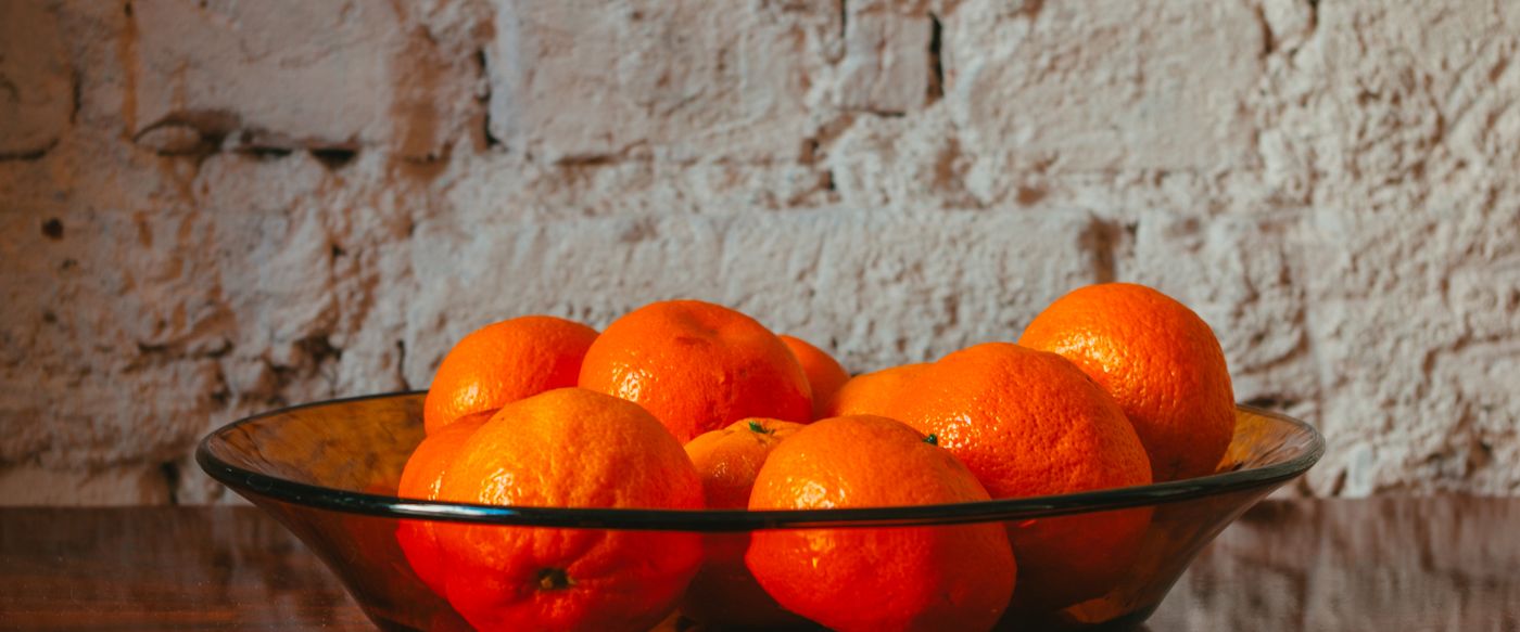 Fresh oranges in a glass bowl on a table, a bright idea for choosing fruity candle scents