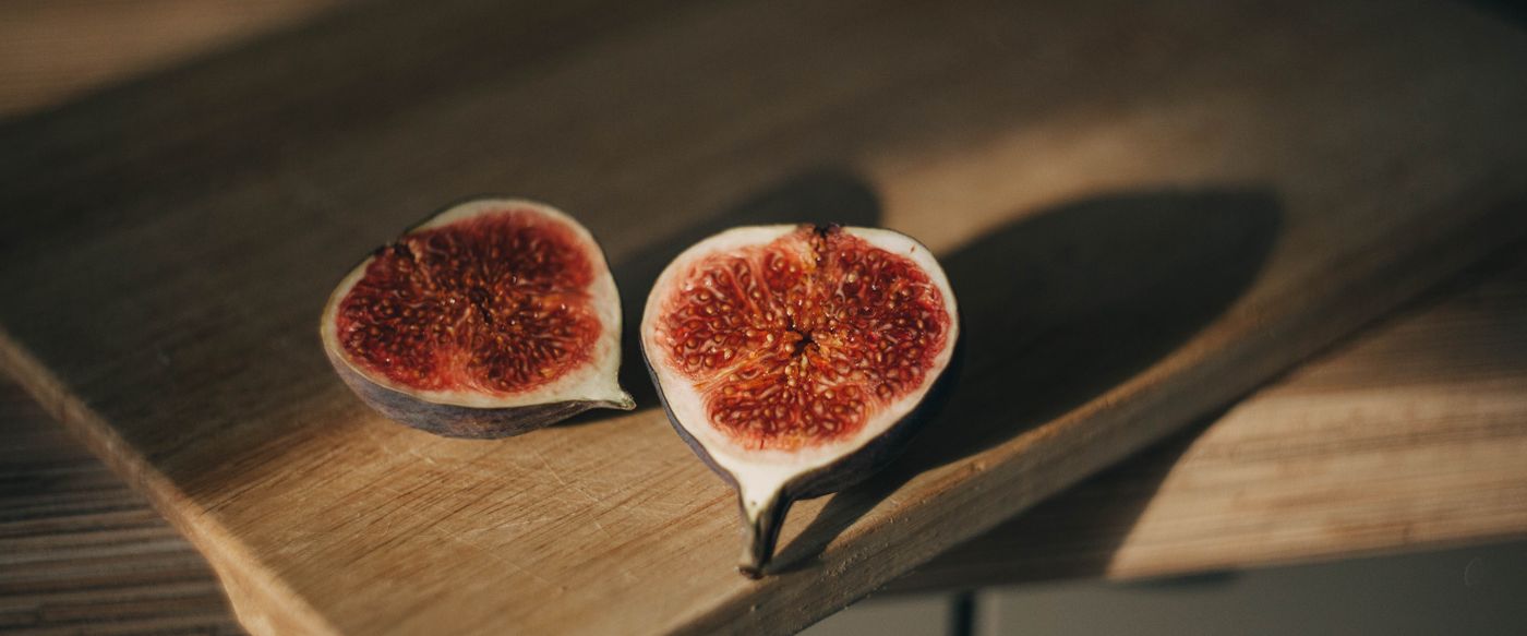 Halved fresh figs on a wooden board, the fruit behind fragrance in candles