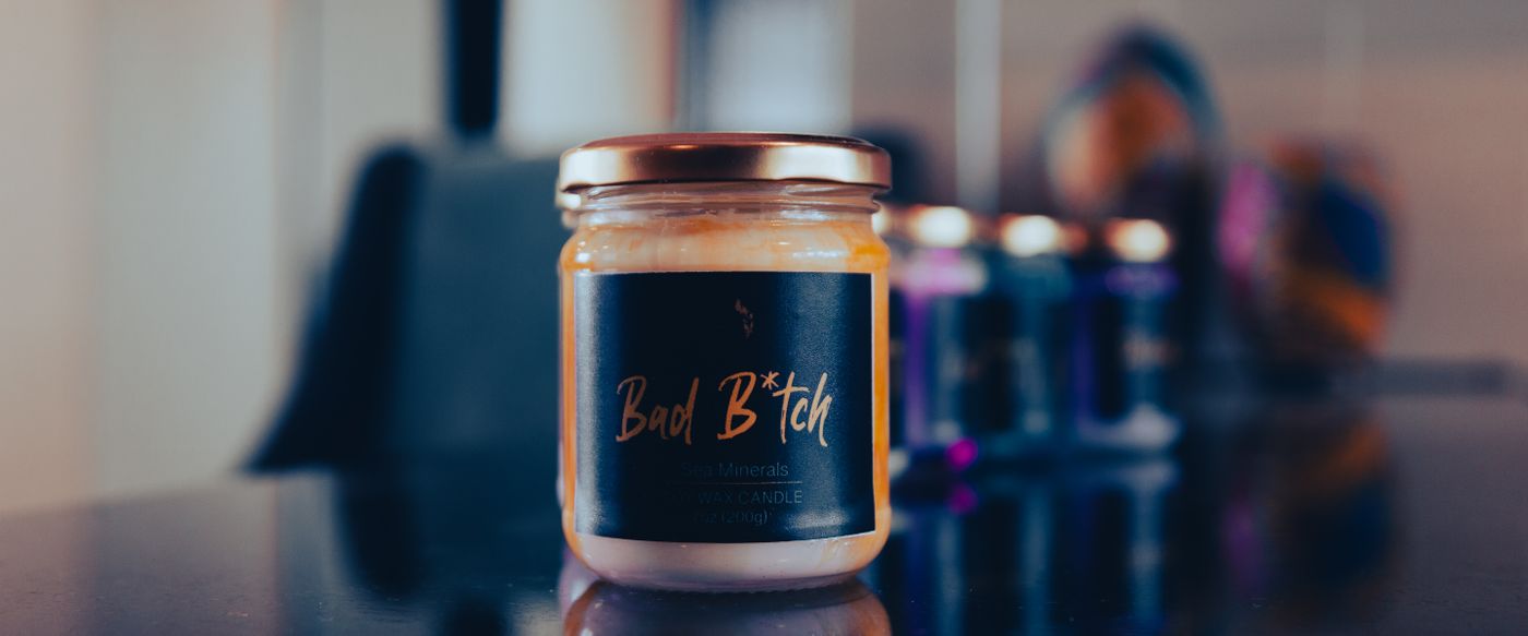 Scented candle in a glass jar on a reflective surface, ready for a candle wick trimmer