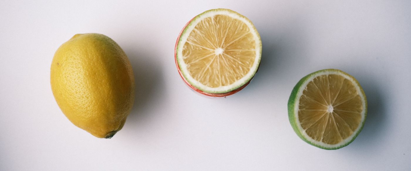 Whole and sliced lemons on a white surface for a fragrance wax melts fresh scent guide