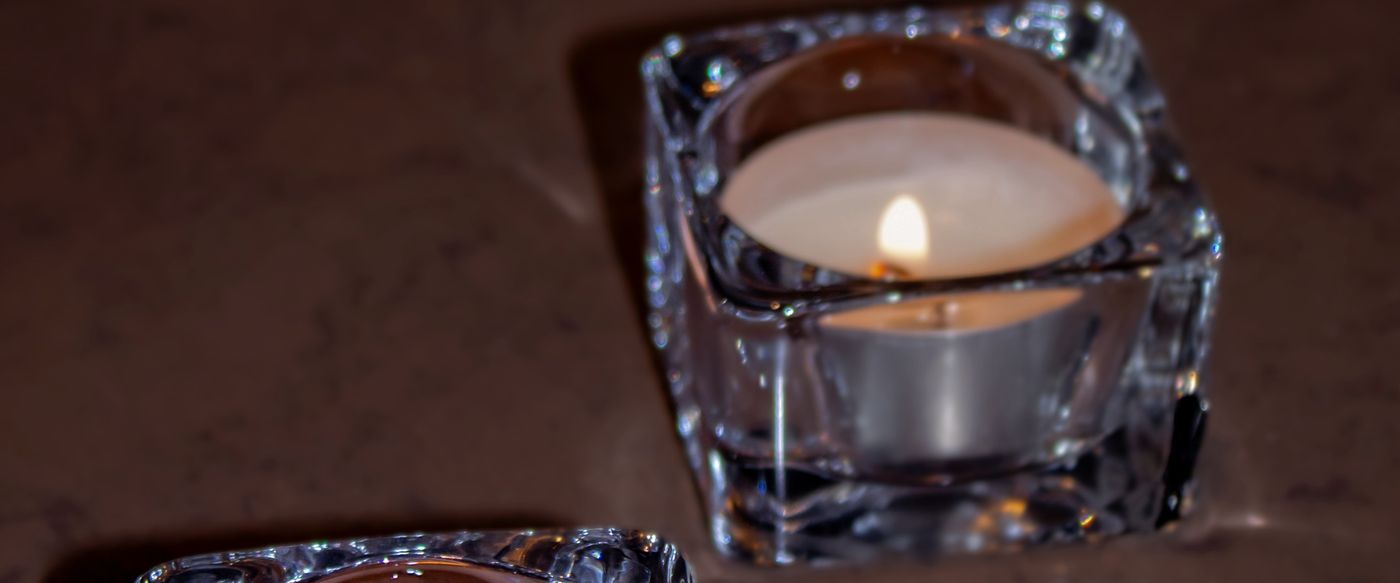 Two glowing candles in square glass holders, a safe setup for scented tea lights