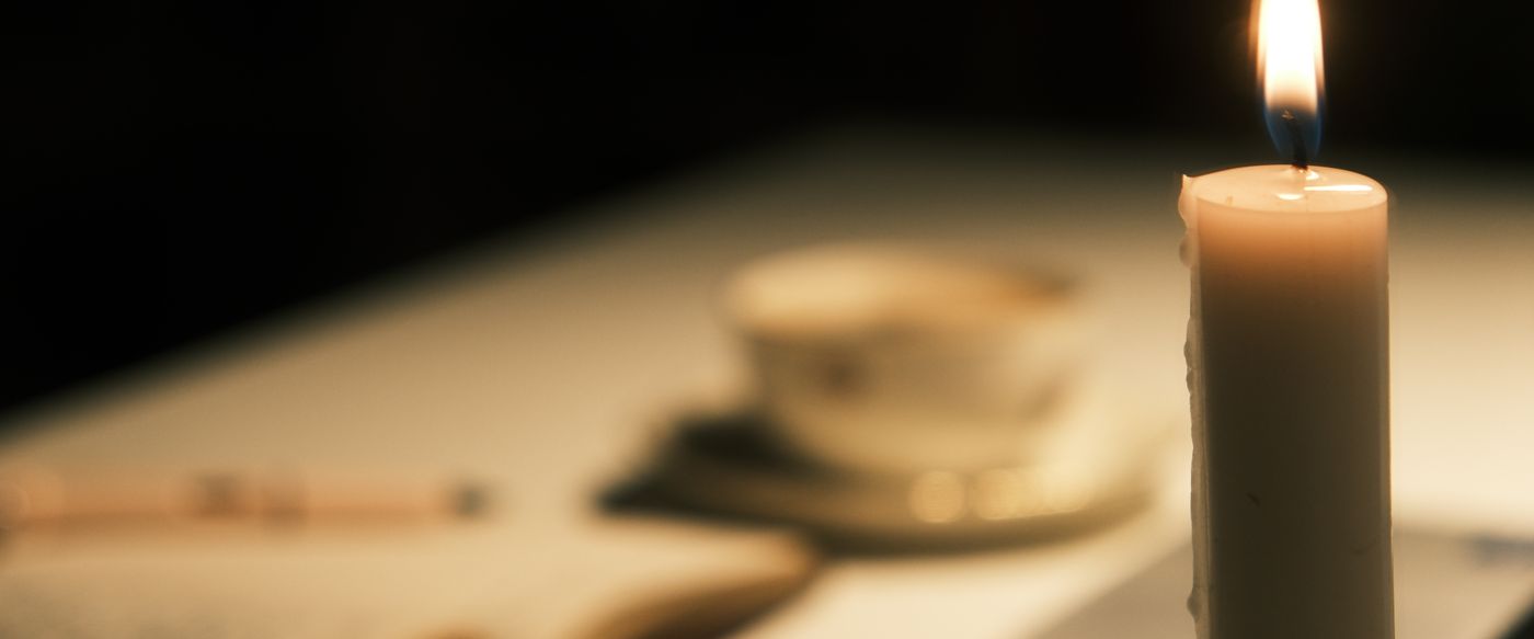 Candlelit table with an open book and a cup of tea, a calm setting for a lavender candle gift
