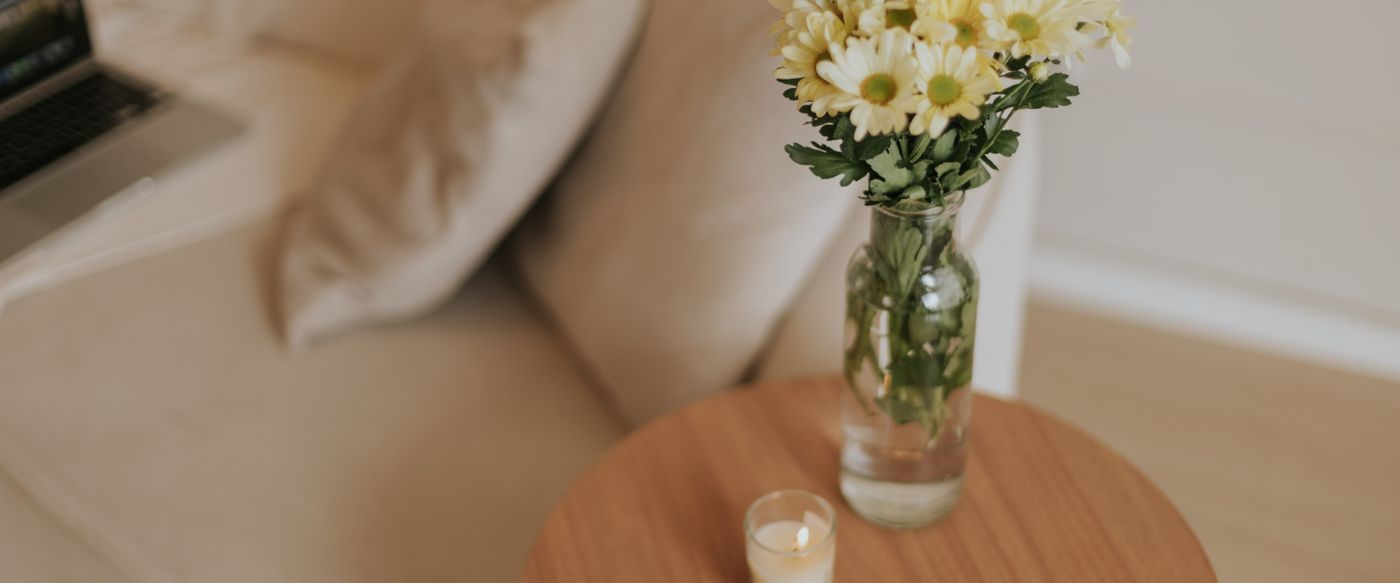 Scented tealight candles and daisies on a wooden table in a minimalist guest room