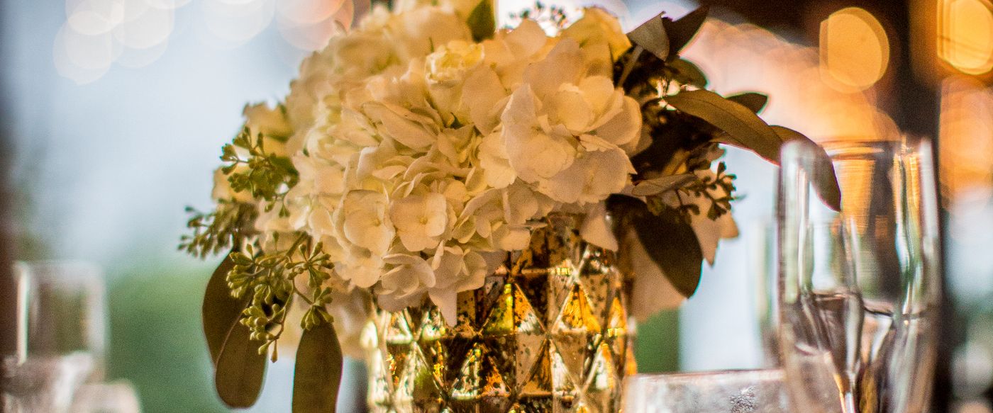White flowers in a gold vase on a styled table for scented candles Australia hosts