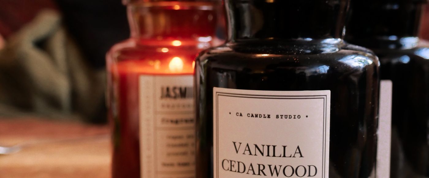 A sandalwood candle glowing warmly on a wooden table this spring