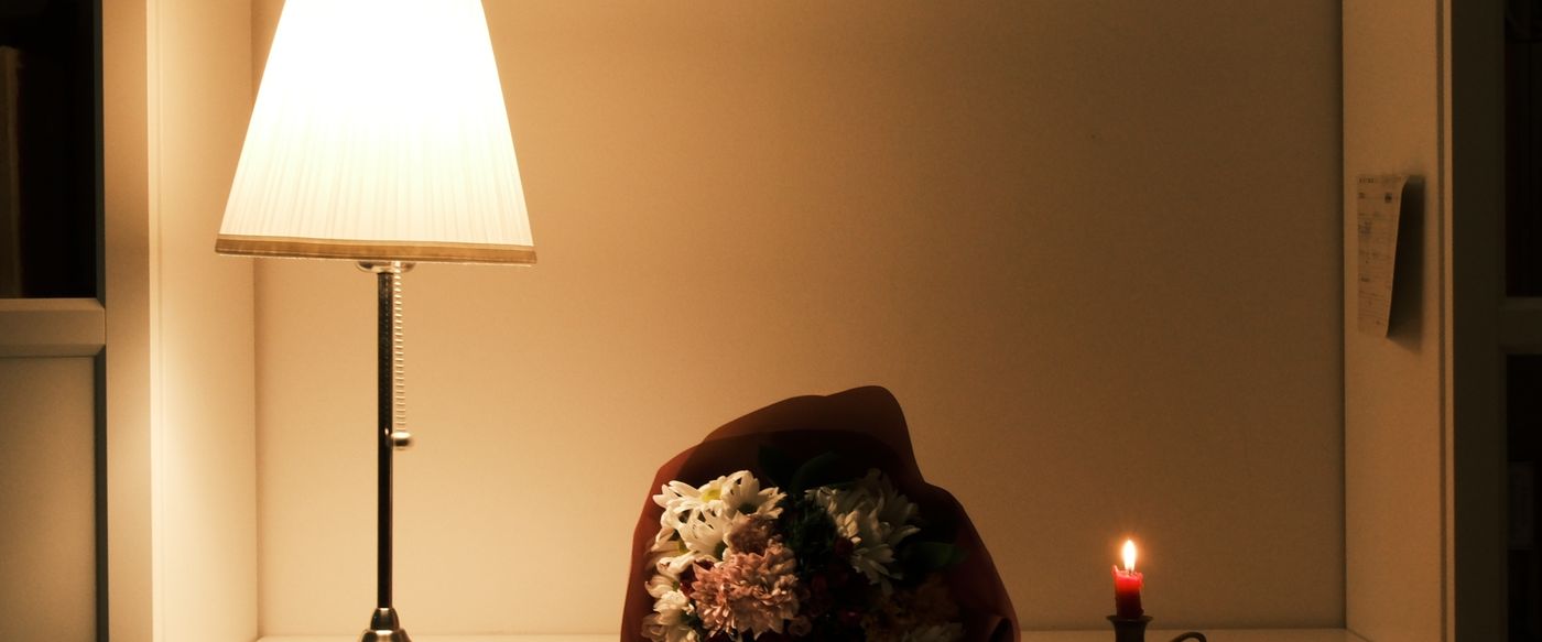 A lit candle, warm lamp and fresh bouquet beside a lavender candle on a spring evening