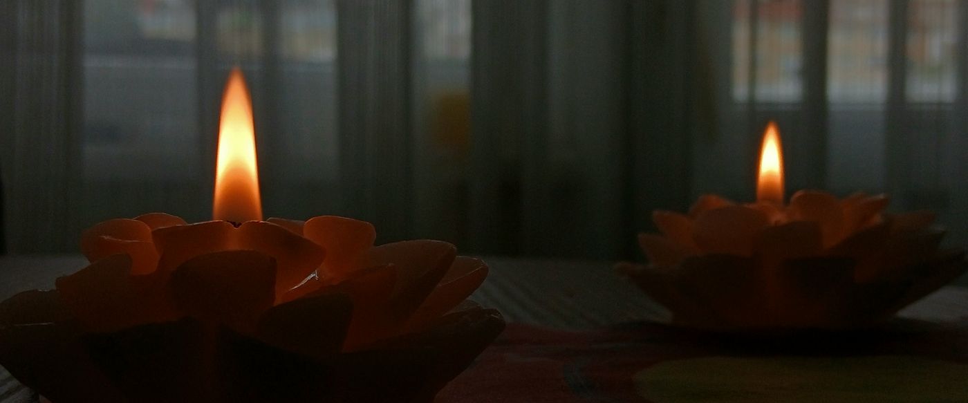 Strong scented candles glowing warmly on a wooden table in a cosy room