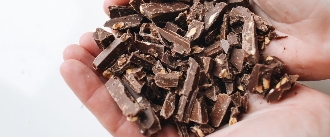Chopped dark chocolate in cupped hands, the sweet scent behind fancy scented candles