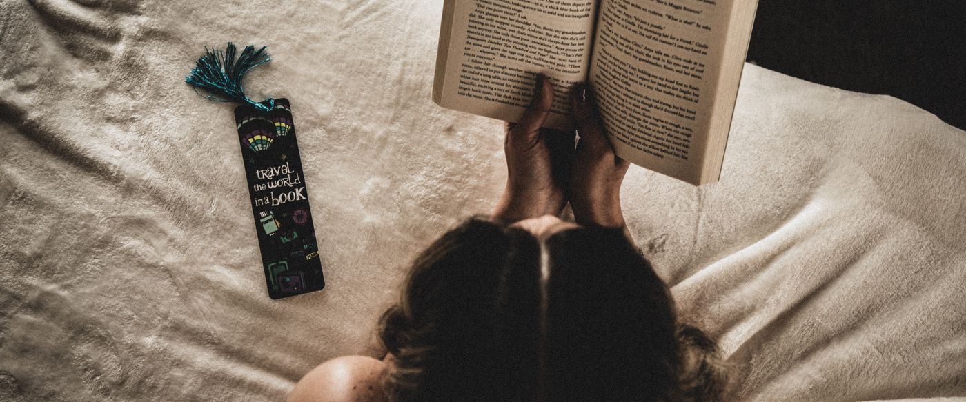 Woman reading in bed on a quiet evening, a slow wind down with scented tealight candles