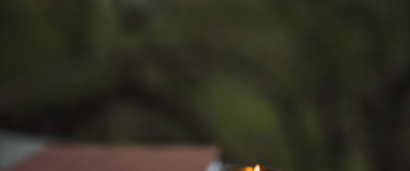 Candle with fragrance burning in a brown glass jar on a wooden surface