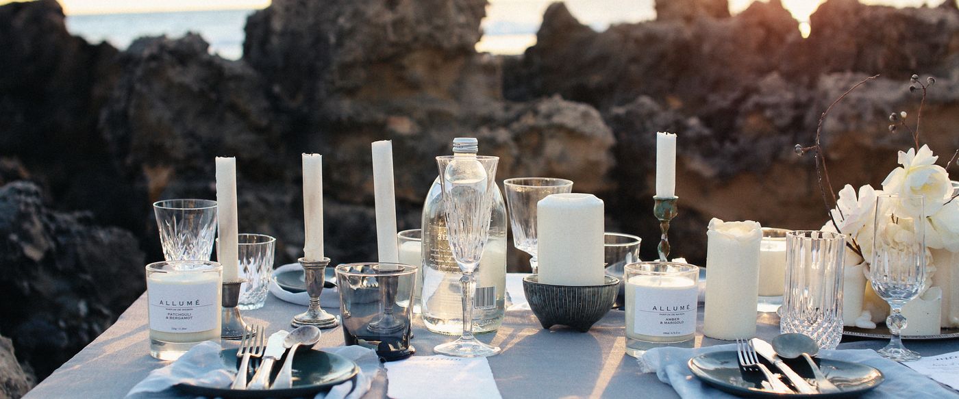 Outdoor table set with white candles and glassware for a summer Christmas fragrance candles setting