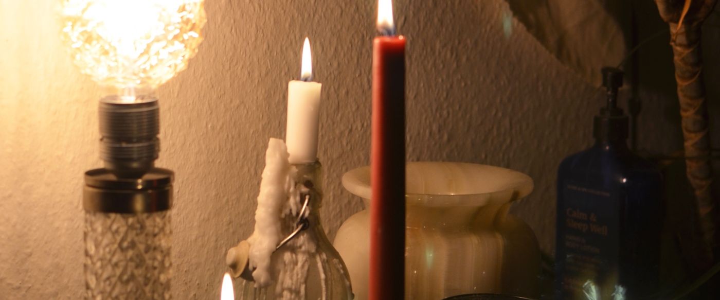 Burning aroma candles Australia homes enjoy, glowing beside a lamp in a dark room