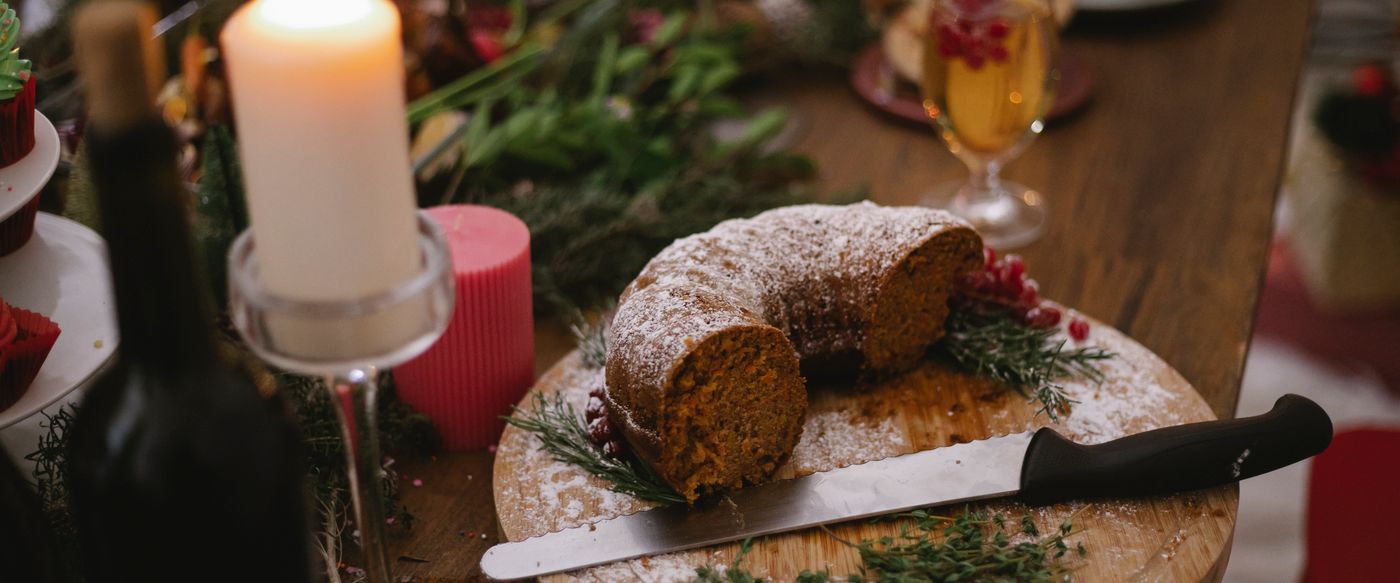 A lit candle beside a cake on a festive table, a caramel and vanilla candle mood