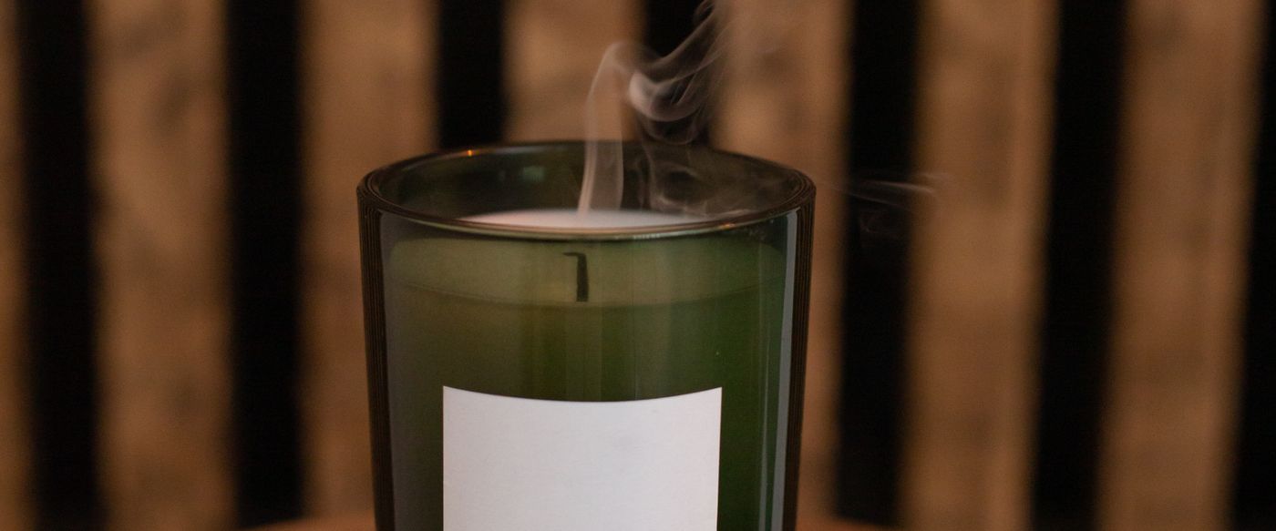Unlit candle in a green glass jar, one of the small candles with lids to store