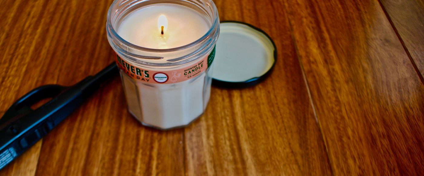 Lit candle with fragrance in a glass jar on a wooden table