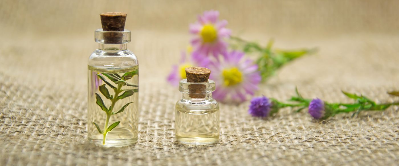 Essential oil bottles and fresh flowers on burlap, the natural florals in candle perfume