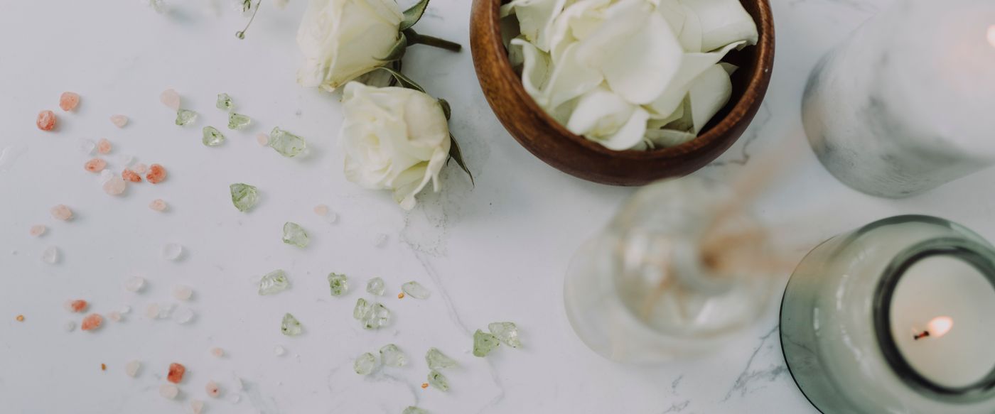 White roses beside a lit candle show how fragrant candles smell floral