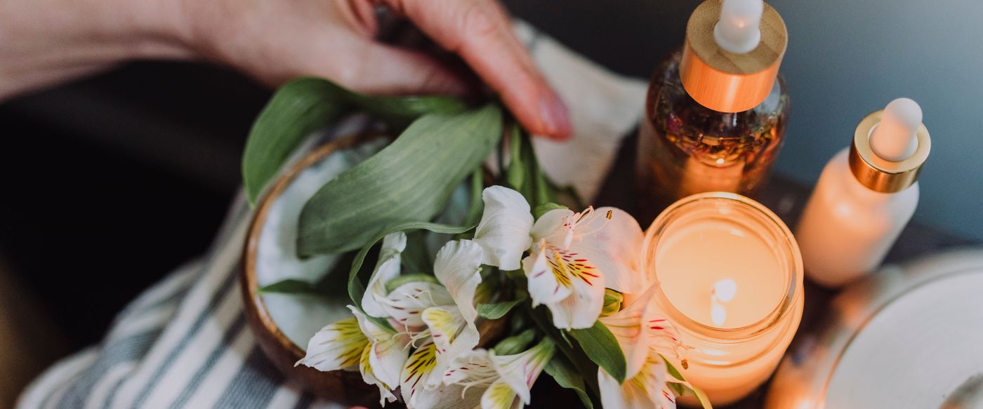 Hands arranging delicate white flowers beside candlelight, a gift idea for best smelling christmas candles
