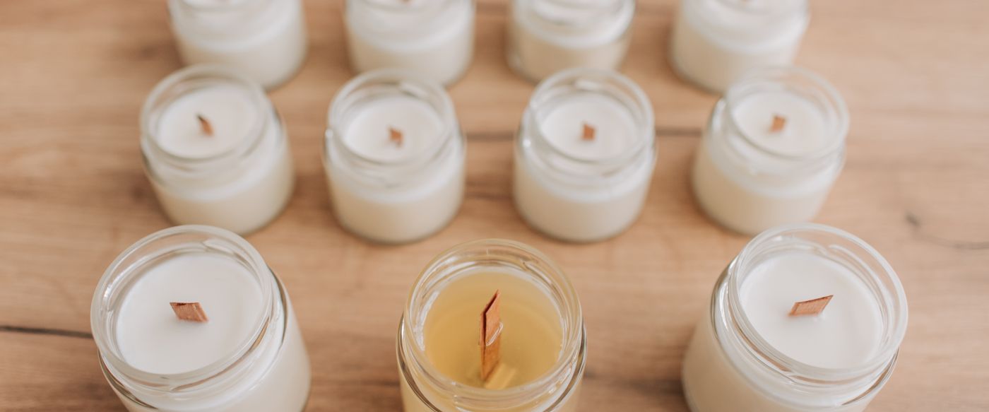 Jar candles in white and yellow wax on a wooden table, for a guide to scented candle wax