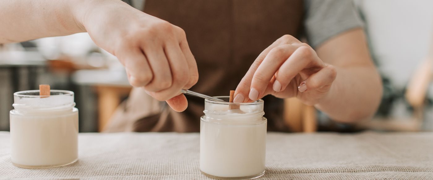 Close-up of hands trimming a candle wick, a clean burn habit for scented soy candles