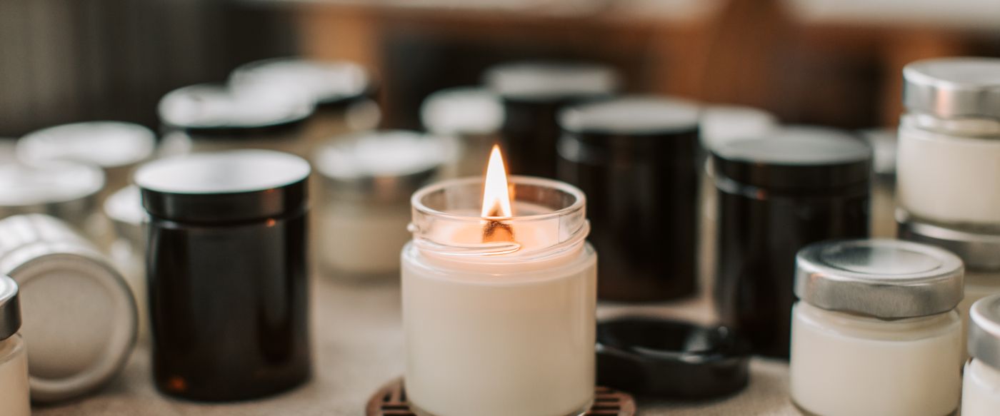 Close-up of a burning handmade candle among glass jars, much like fruity candles being made