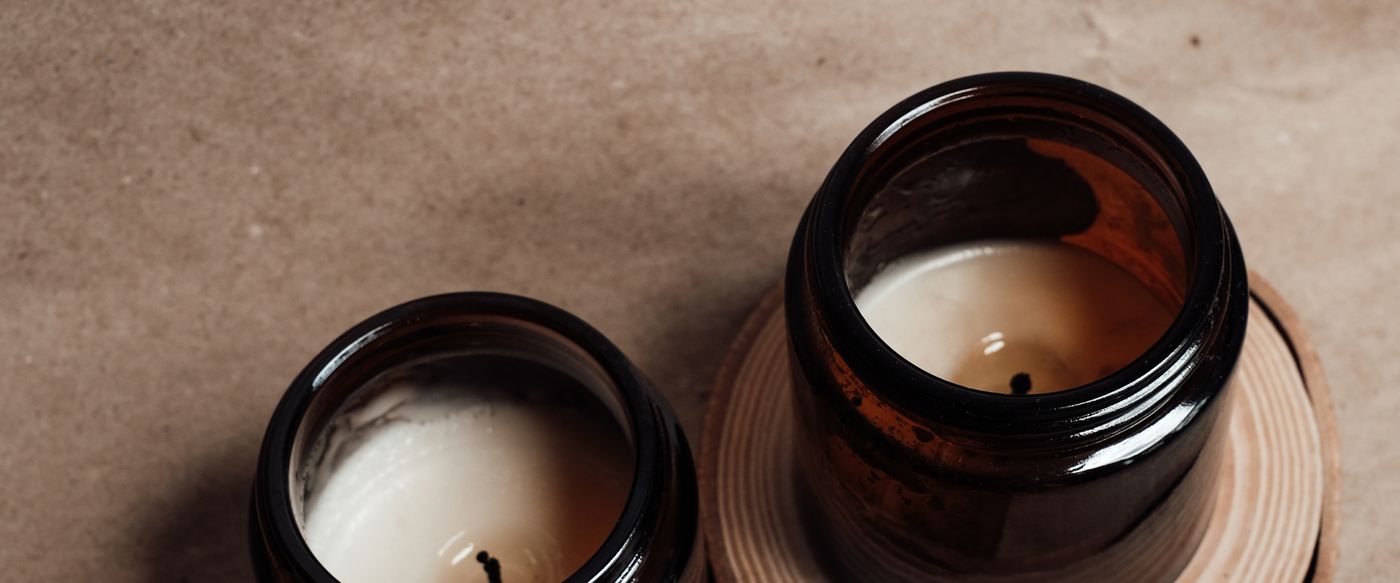 Three scented candles in amber glass jars grouped on a wooden slice, styled for scented candles online shoppers