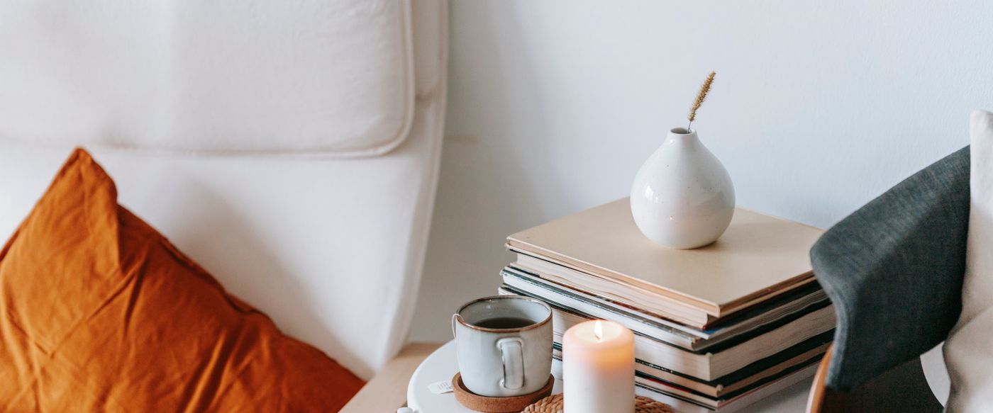 Armchair with books, a lit candle and a cup of tea on a calm spring evening