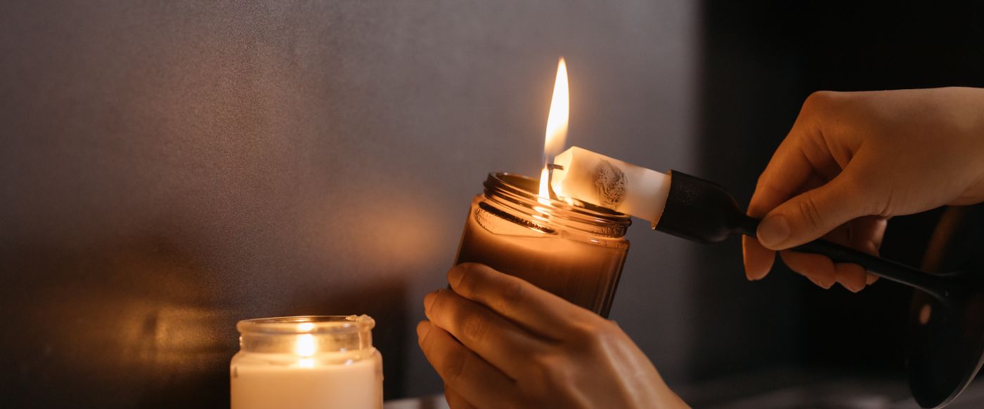 Hands lighting candles indoors, an electric candle lighter makes a calm evening routine