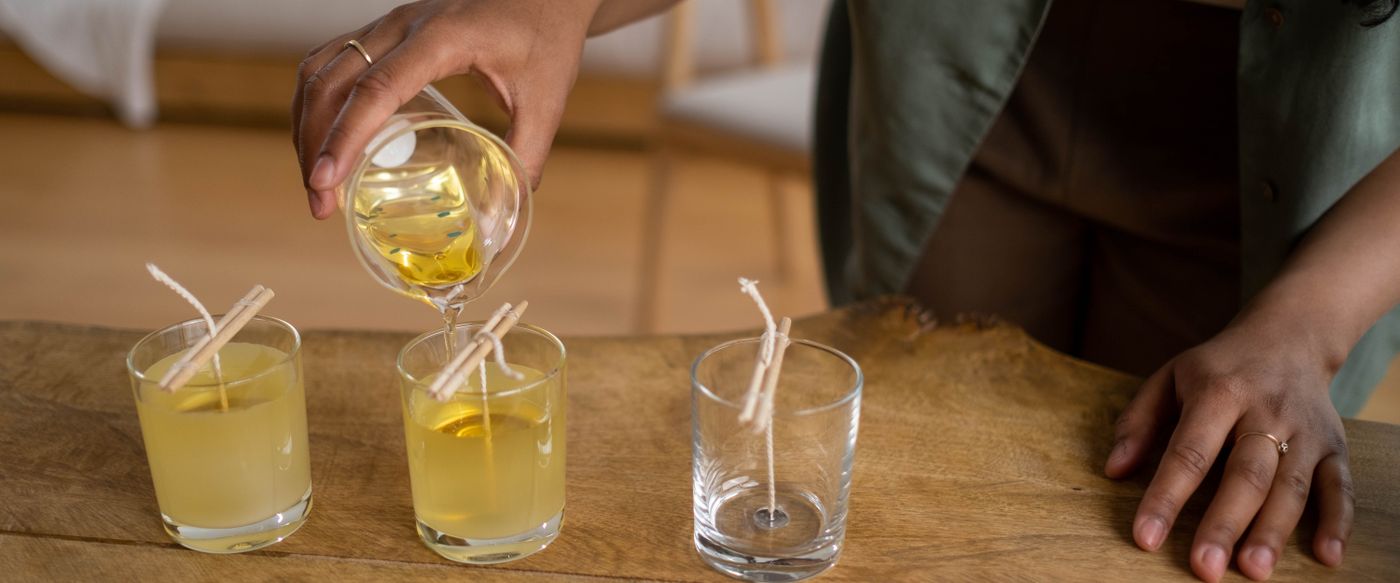 Candle maker pouring melted wax into glass jars, showing how scented candle wax is made